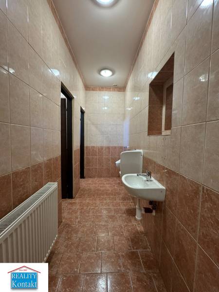 Badezimmer in Geschäftsräumen mit Waschbecken und Fliesen in Brauntönen.