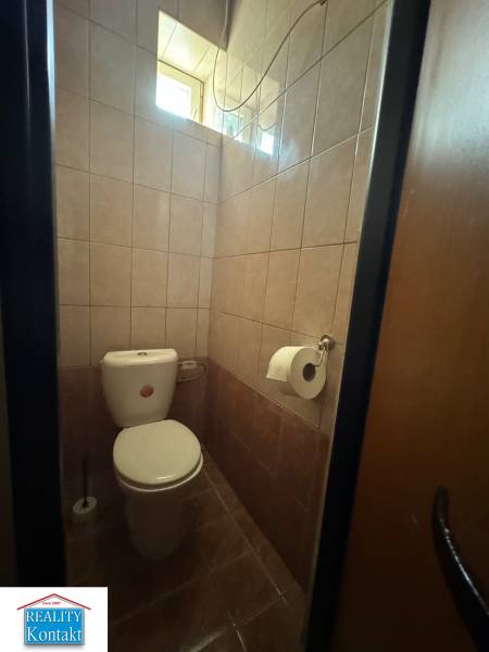 Eine Toilette mit gefliesten Wänden in Geschäftsräumen, mit einem Fenster für natürliches Licht.