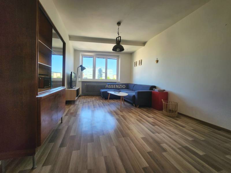 Wohnzimmer in einer 2-Zimmer-Wohnung mit einer Eckcouch und Holzboden.