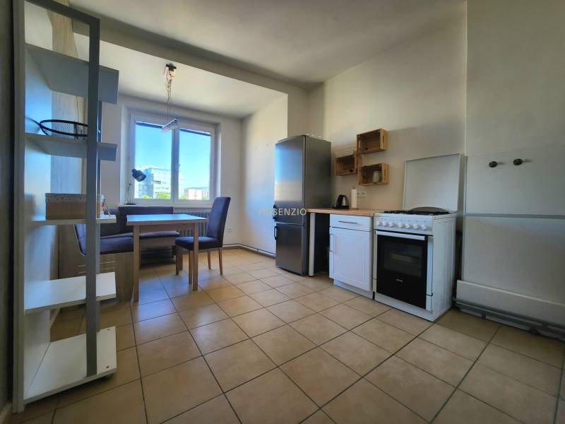 Küche in einer 2-Zimmer-Wohnung mit Esstisch, Geräten und großem Fenster.