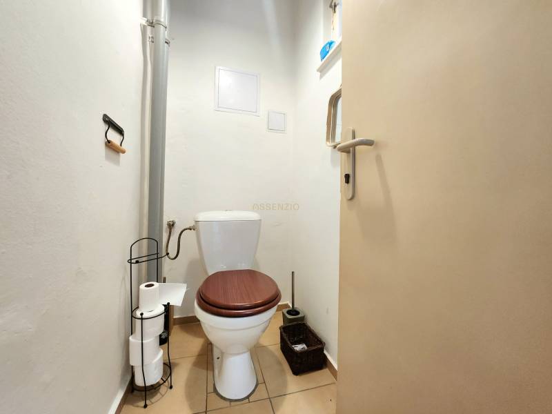 Badezimmer in einer 2-Zimmer-Wohnung, mit Toilette und Toilettenpapierhalter.