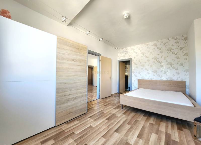 Schlafzimmer mit Holzboden, Bett und Einbauschrank in einer 2-Zimmer-Wohnung.