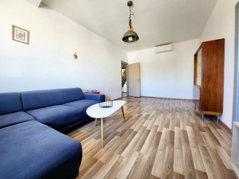 Wohnzimmer mit einem blauen Sofa, Holzboden und minimalistischen Möbeln in einer 2-Zimmer-Wohnung.