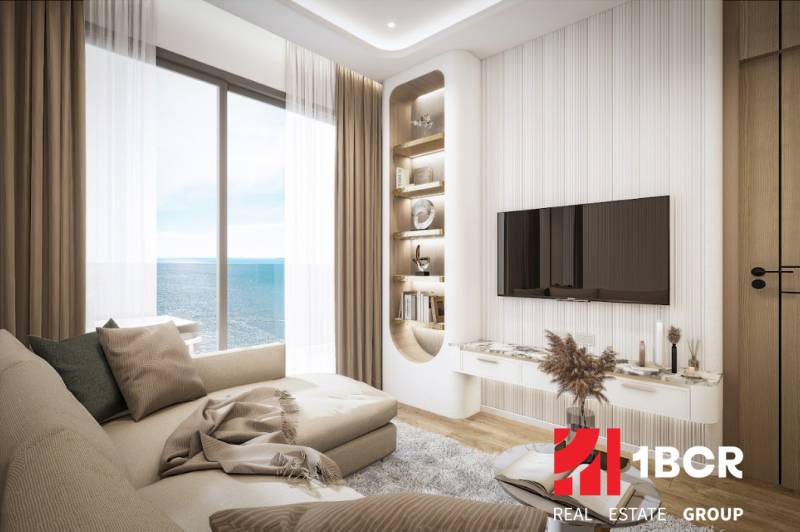 Wohnzimmer in einer 3-Zimmer-Wohnung mit Meerblick, bequeme Couch, Fernseher an der Wand.