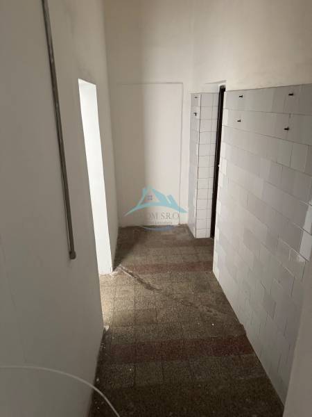 Schmaler Innenraum mit Fliesenboden und Wandverkleidung in Geschäftsräumen.