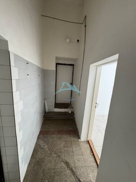 Ein enger Flur mit gefliesten Wänden und Licht in Geschäftsräumen.