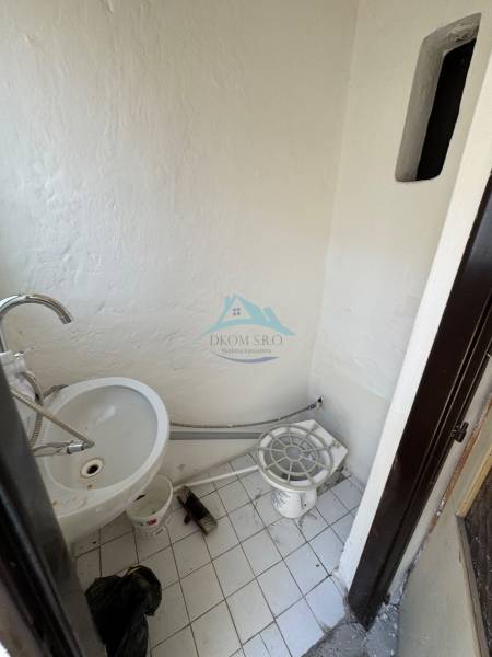 Ein kleiner Innenraum mit Waschbecken und weißen Fliesen in Geschäftsräumen.
