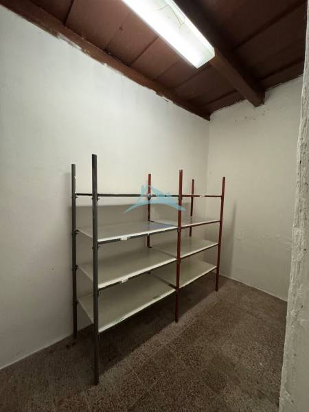 Lagerraum in Geschäftsräumen mit einem Metallregal und Beleuchtung an der Decke.