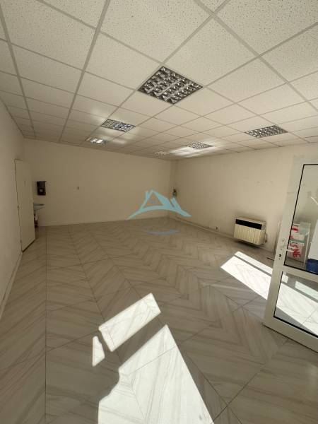 Leerer Geschäftsraum mit Keramikfliesen und abgehängter Decke aus Gipskarton.