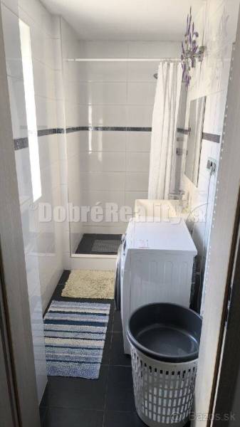 Badezimmer in einer 2-Zimmer-Wohnung, mit Waschmaschine und Duschkabine.