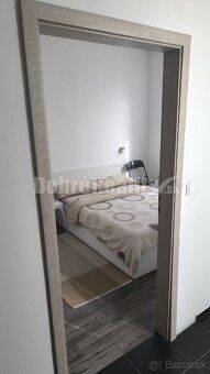 Ein Zimmer mit einem eingebauten Bett und einem Nachttisch in einer Zweizimmerwohnung.