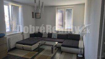 Wohnzimmer in einer 2-Zimmer-Wohnung mit großem Sofa und Fenster.