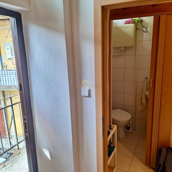 In der 1-Zimmer-Wohnung sieht man das Badezimmer mit Toilette und die Tür, die zum Balkon führt.