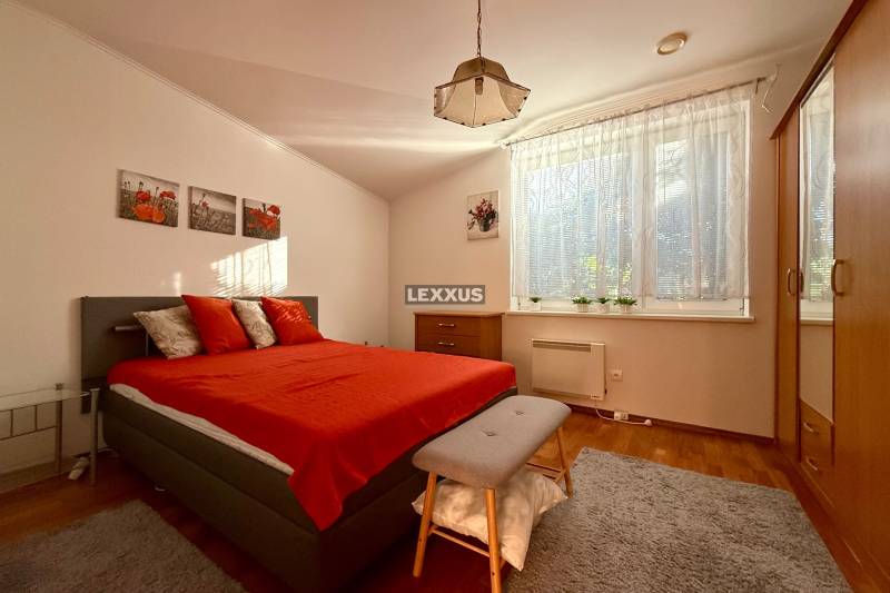 Ein Schlafzimmer in einem Einfamilienhaus mit einem roten Bett, einem Kleiderschrank und einem großen Fenster.