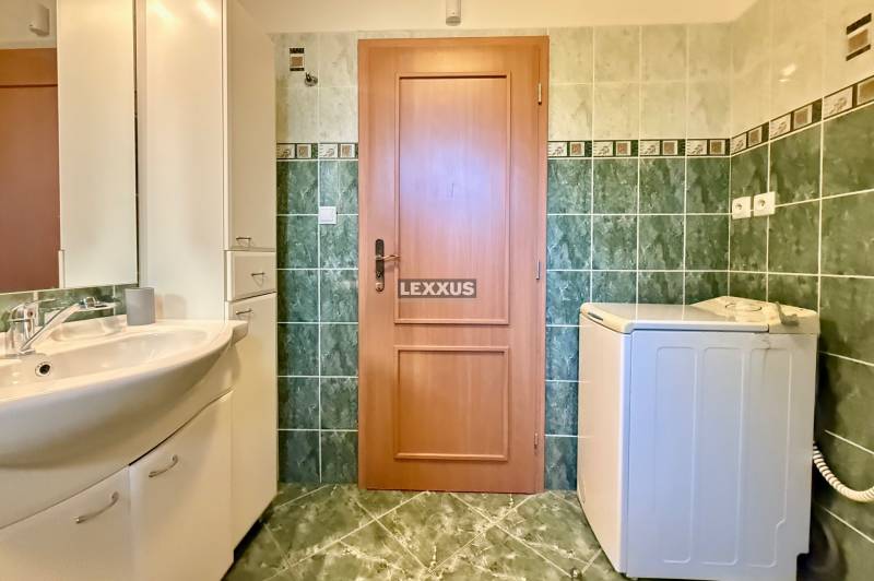 Badezimmer mit Waschmaschine, Waschbecken und Fliesen in einem Einfamilienhaus.