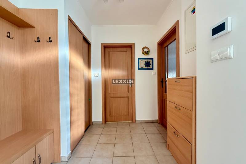 Ein Flur in einem Einfamilienhaus mit Holzmöbeln und Fliesenboden.