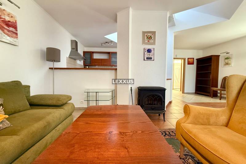 Wohnzimmer mit Kamin, grünem Sofa und Küchenzeile in einem Einfamilienhaus.