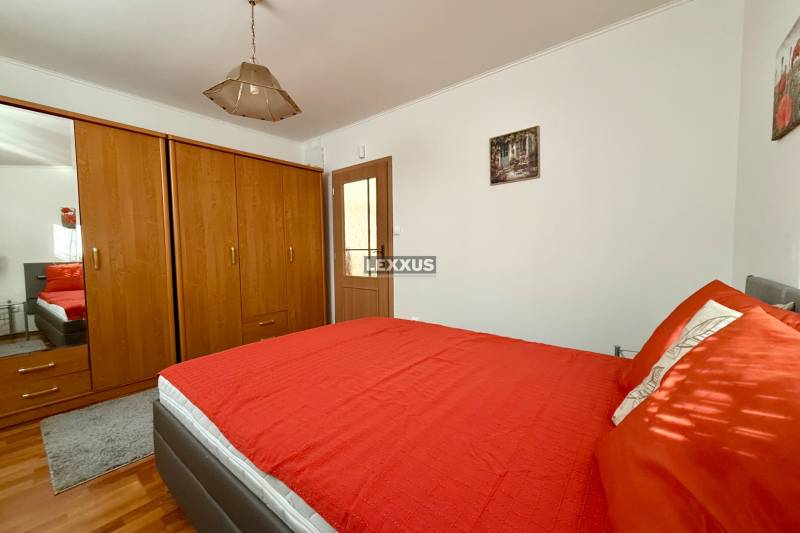 Schlafzimmer mit einem Holzschrank, einem roten Bett und einer Deckenleuchte in einem Einfamilienhaus.