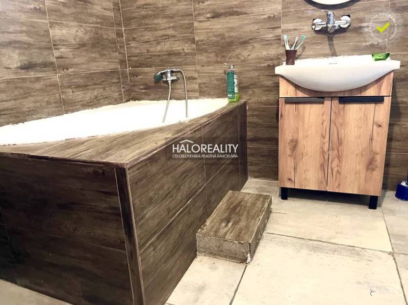 Ein Badezimmer in einem Einfamilienhaus mit eingebauter Badewanne und einem Waschbecken aus Holz.