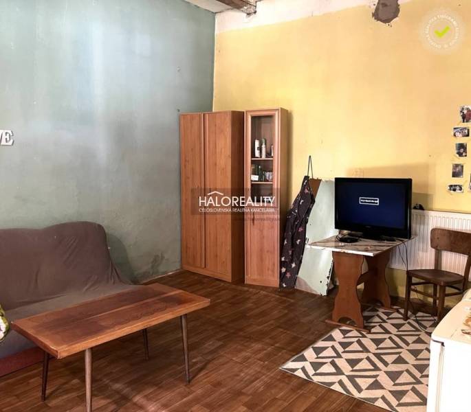 Wohnzimmer mit Sofa, Schrank und Fernseher in einem Einfamilienhaus, einfache Einrichtung.