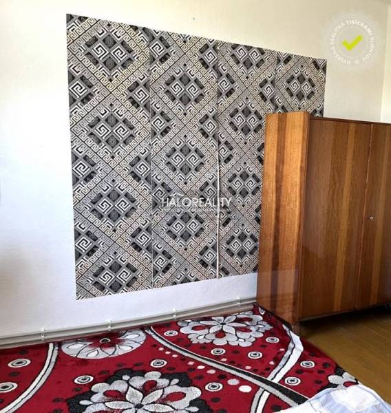Schwarz-weiße geometrische Tapete, Holzschrank und Blumenmusterteppich in einem Einfamilienhaus.