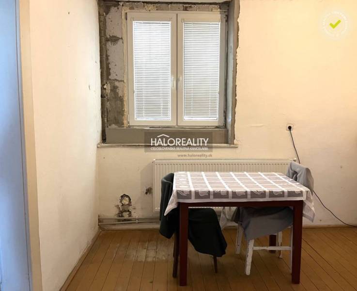 Ein Zimmer eines Einfamilienhauses mit einem Fenster, einem Tisch und Stühlen, einfaches Interieur.
