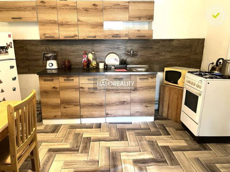 Küche in einem Einfamilienhaus mit Holzschränken, Herd und Kühlschrank.