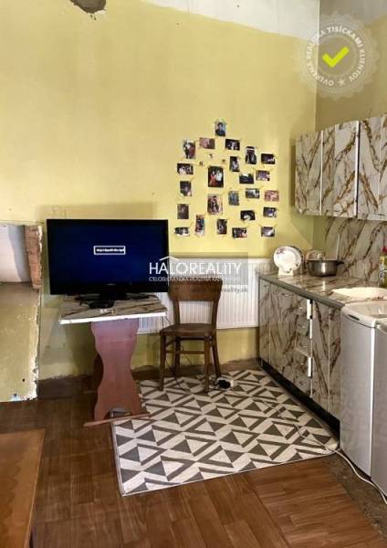 Küche in einem Einfamilienhaus mit Fernseher, Fotos an der Wand und Herd.
