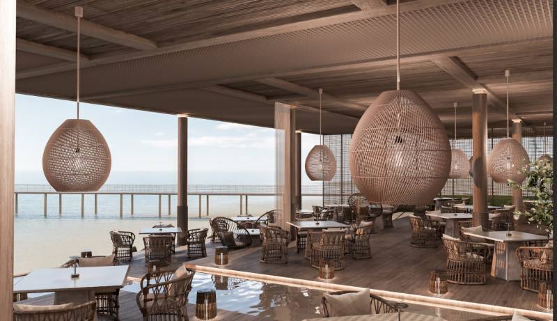 Ein luxuriöses Restaurant mit Blick auf den Ozean, stilvolle Hängeleuchten, komfortable Sitzgelegenheiten.