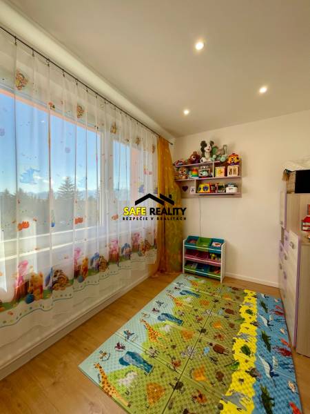 Kinderzimmer in einer Vierzimmerwohnung mit Spielzeug und einem bunten Teppich auf dem Boden.