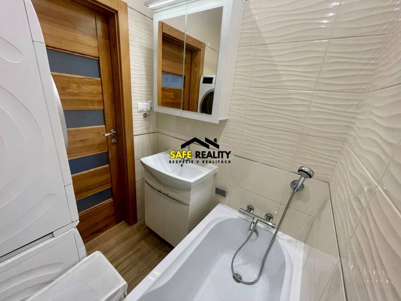 Badezimmer in einer 4-Zimmer-Wohnung mit Waschmaschine, Badewanne, Waschbecken und Spiegel.