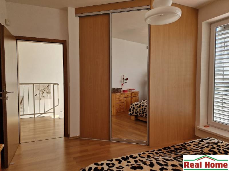 Innenraum eines Einfamilienhauses mit Einbauschrank, Spiegel und Leopardenmustern auf dem Bett.