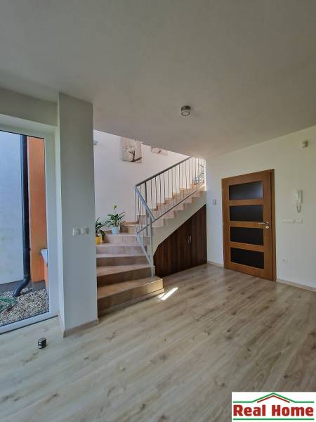 Ein heller Flur mit einer Holztreppe und einem Geländer in einem Einfamilienhaus.