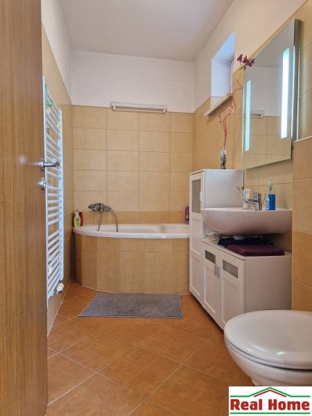 Badezimmer im Einfamilienhaus mit Eckbadewanne, Schrank, Waschbecken und Toilette.