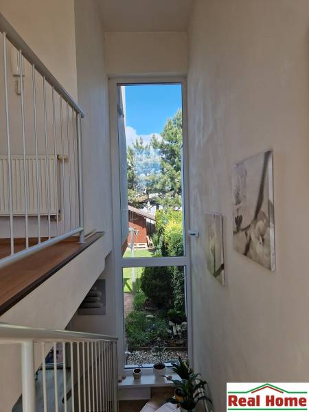 Innenraum eines Einfamilienhauses mit großem Fenster, Blick in den Garten und Treppe.