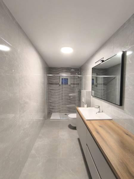 Badezimmer mit Dusche und Waschbecken in einer 4-Zimmer-Wohnung, helle Fliesen.