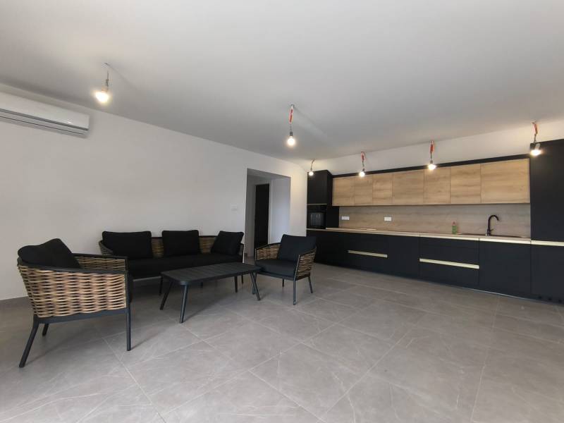 Wohnbereich einer 4-Zimmer-Wohnung mit dunklen Möbeln und einer Küche mit Holzelementen.