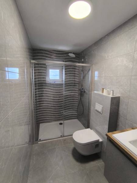 Badezimmer mit Dusche in einer 4-Zimmer-Wohnung, mit Fliesen und Fenster.