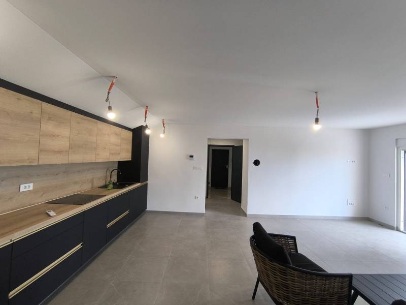 Innenraum einer 4-Zimmer-Wohnung mit minimalistischer Küche und schwarzem Sessel im Wohnzimmer.