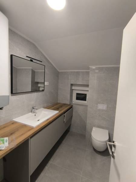 Badezimmer in einer 4-Zimmer-Wohnung mit Dusche, Waschbecken, Spiegel und Toilette.