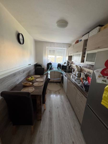Küche in einer 3-Zimmer-Wohnung mit Esstisch, Holzboden und Fenster.