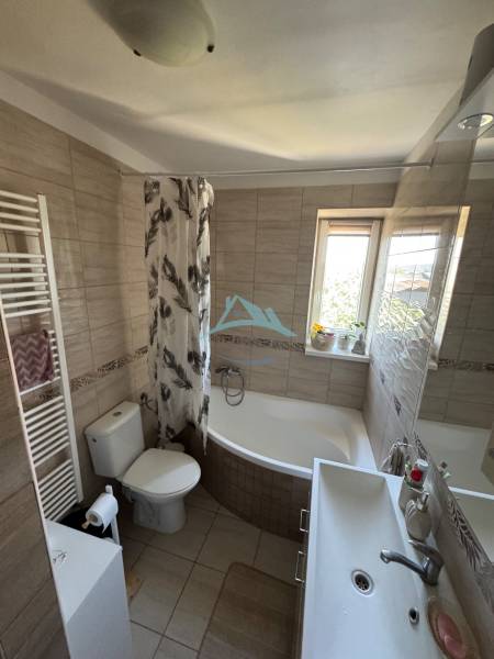 Badezimmer in einer 3-Zimmer-Wohnung mit Badewanne, Waschbecken und Fenster für natürliches Licht.