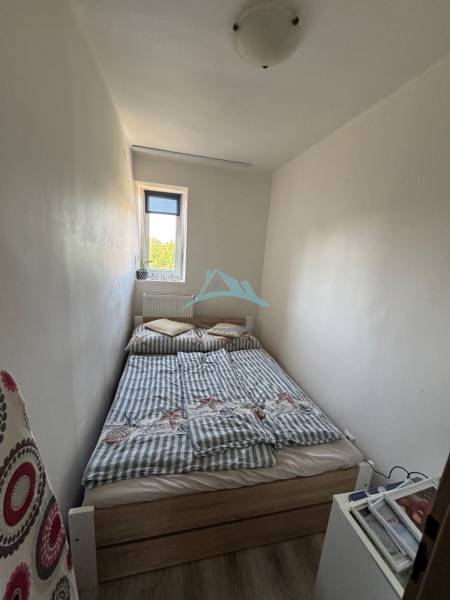 Ein kleines Schlafzimmer mit einem Bett in einer 3-Zimmer-Wohnung, einfache Einrichtung und weißes Interieur.
