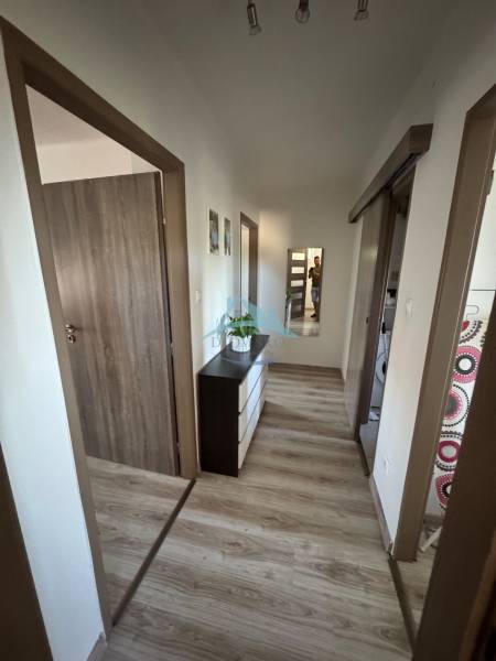 Flur in einer 3-Zimmer-Wohnung mit Spiegel, Holzboden und Türen.