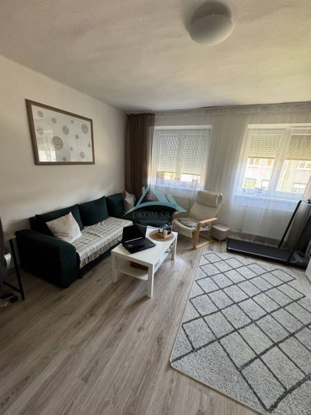 Helles Wohnzimmer in einer 3-Zimmer-Wohnung mit Sofa, Sessel und Tisch auf hellem Boden.
