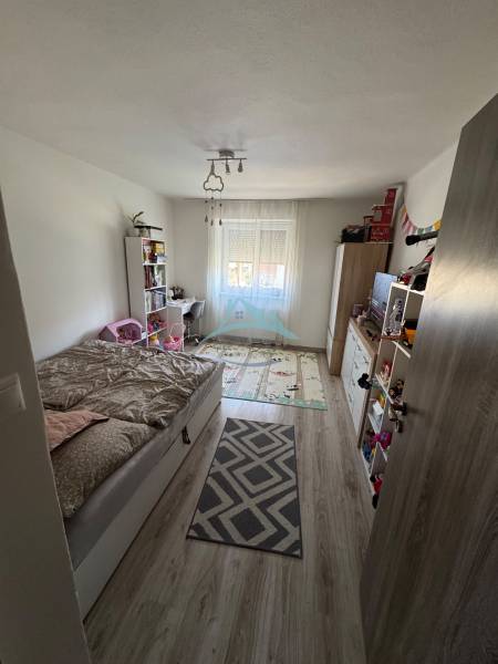 Kinderzimmer mit Bett und Fenster in einer 3-Zimmer-Wohnung, heller Holzboden.