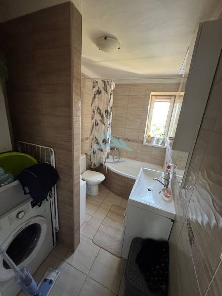 Badezimmer mit Waschmaschine, Badewanne und Waschbecken in einer 3-Zimmer-Wohnung.