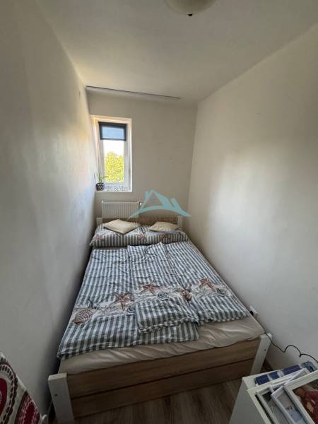 Ein kleines Schlafzimmer mit einem schmalen Fenster und einem Bett in einer 3-Zimmer-Wohnung.