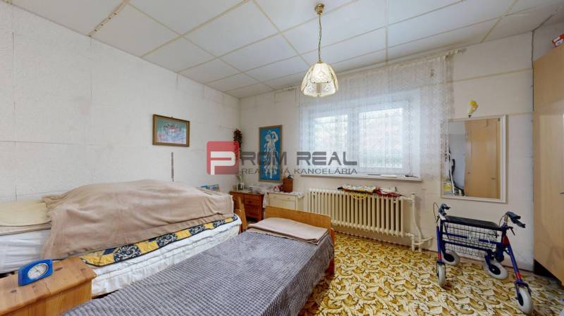 Zimmer mit Bett, Teppich und Lauflernhilfe in einem Einfamilienhaus.