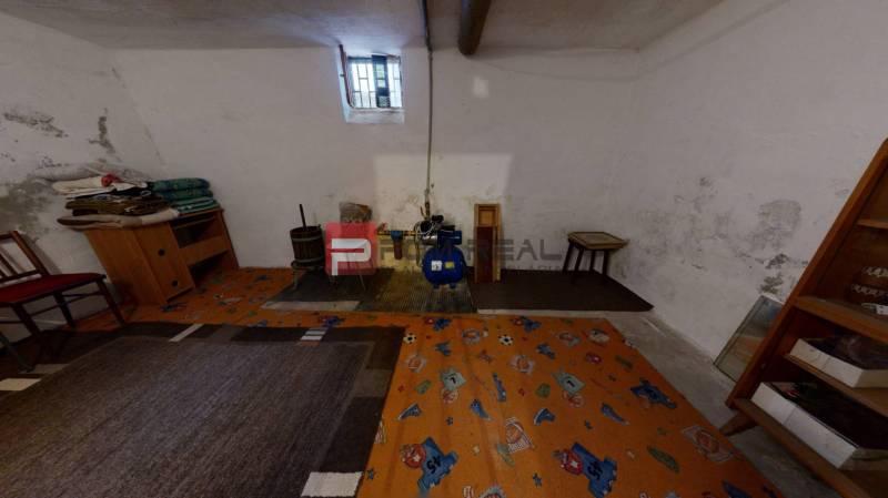Keller eines Einfamilienhauses mit kleinem Fenster, Teppichboden und Inneneinrichtung einschließlich Sessel.